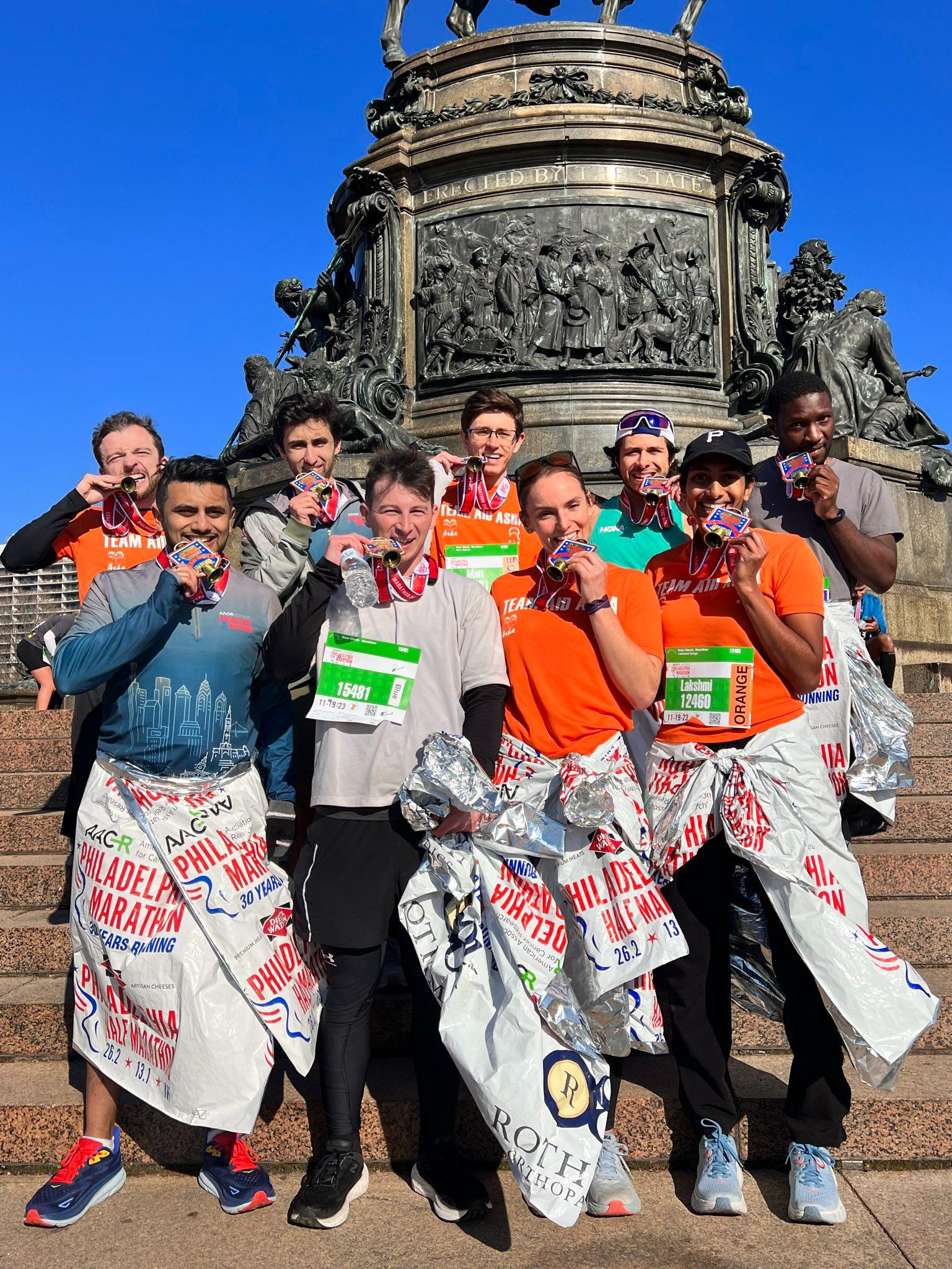 Team biting medals at Philadelphia Marathon
